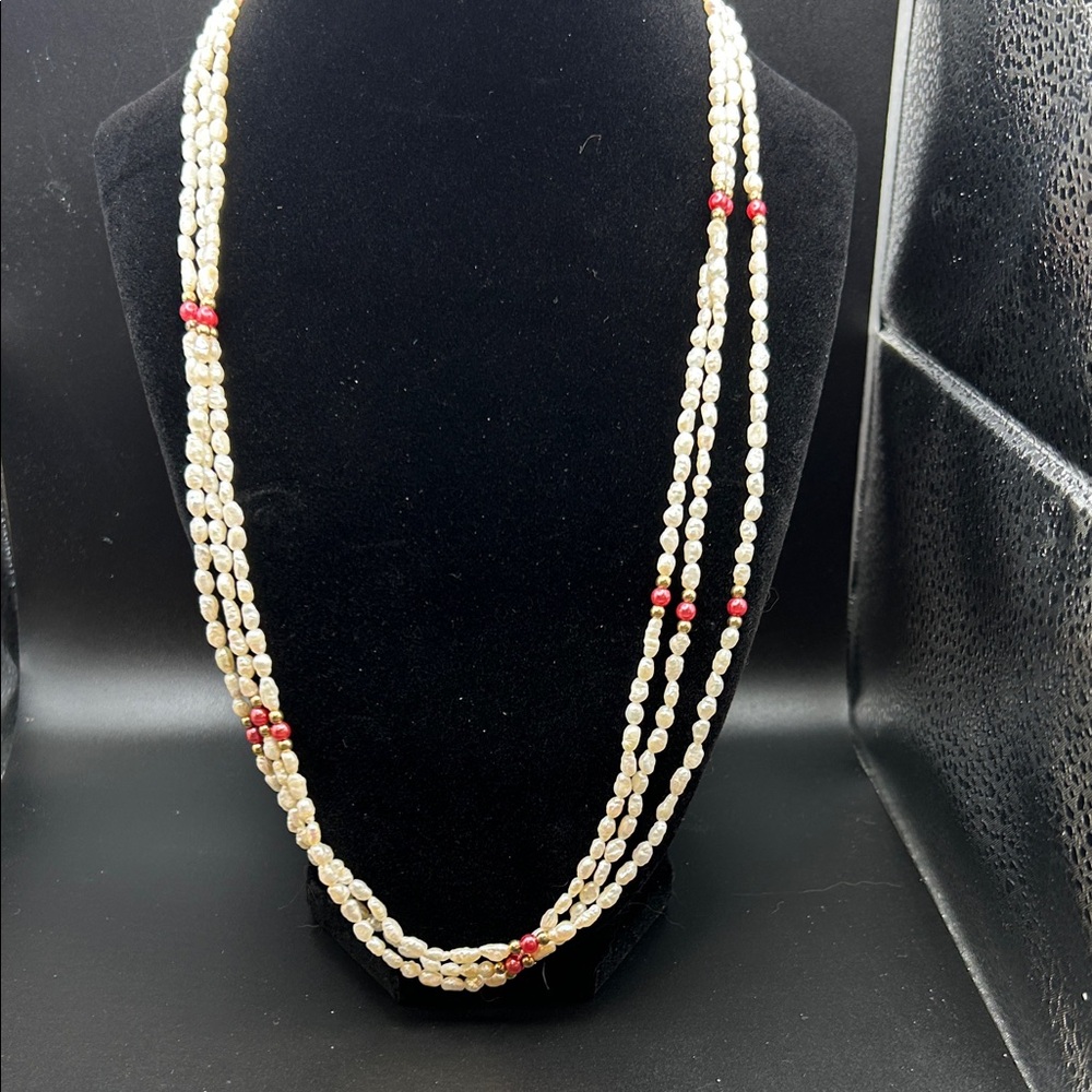 Three strand white bead necklace with pink and gold color accents. 12”